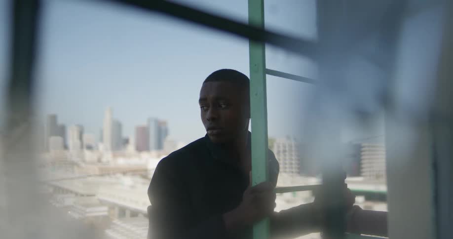 A man stands on the ladder of a buildings rooftop