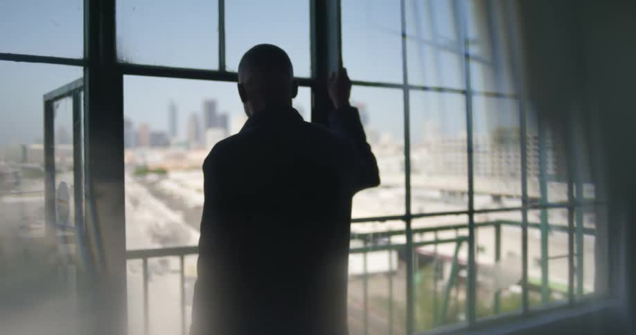 A mans silhouette standing in a door frame looking out over a city