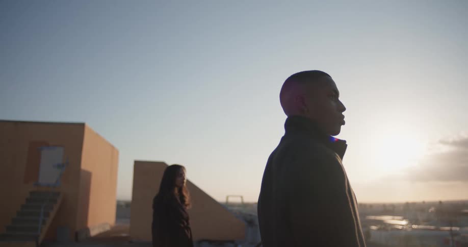 Three people stand as sunshines in sky over red tinted horizon