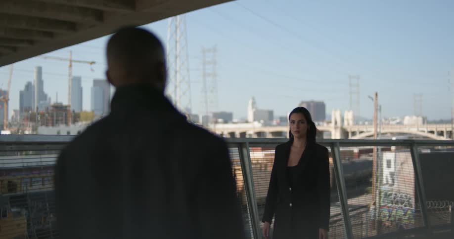 A man and woman look back at each other after passing by on a pedestrian bridge