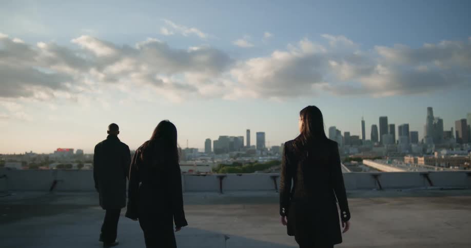 People walk across a building rooftop with views of downtown