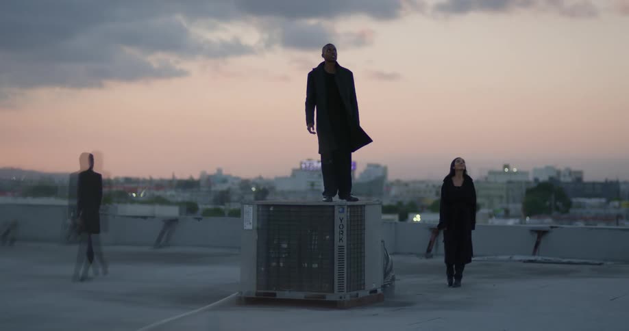 A group of friends dance around the top of a building downtown