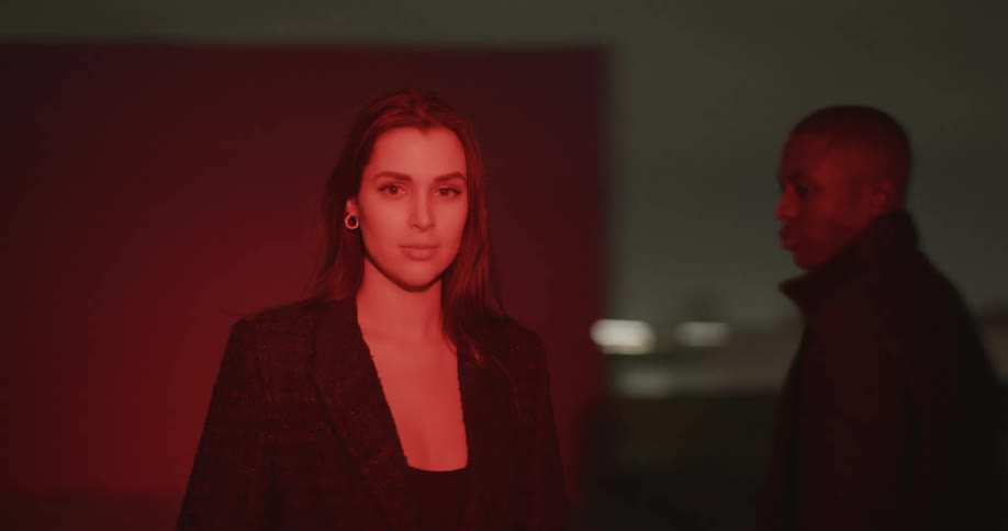 Red flashing lights shine across people standing outdoors at night