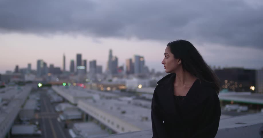 A woman stands near the edge of a high rise building