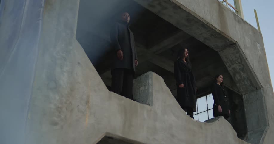Three people standing on the edge of a concrete opening staring off into the distance