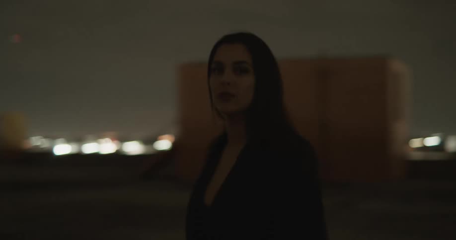 A woman walks back and forth on top of a high rise rooftop