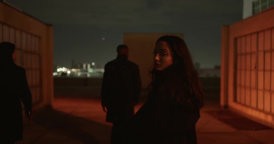 A man walking and two women talking behind him on top of a building with flashing lights