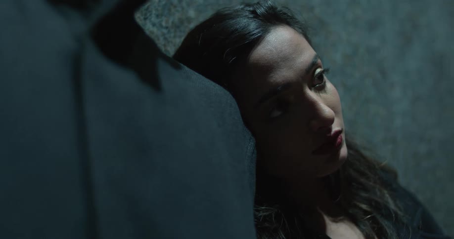 A woman lays her head on the shoulder of a mannequin or something and stares into the distance