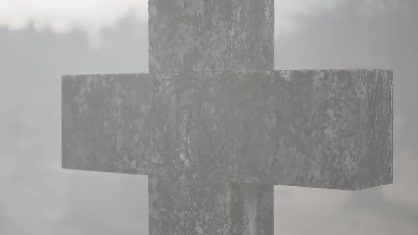 A cross in a cemetery standing in the mist