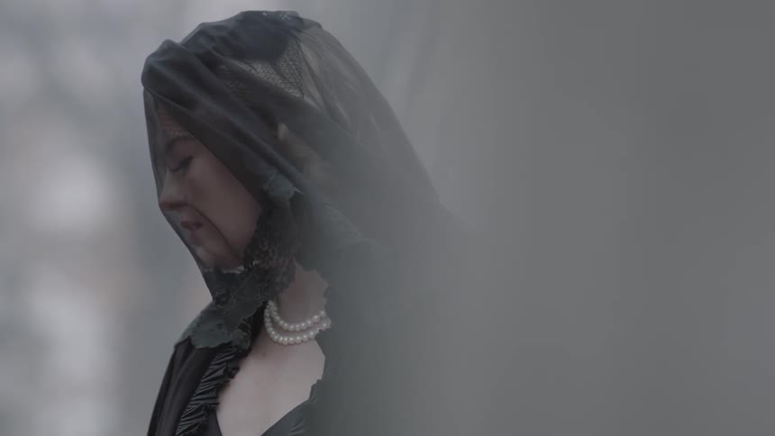 A woman in a black veil looks down