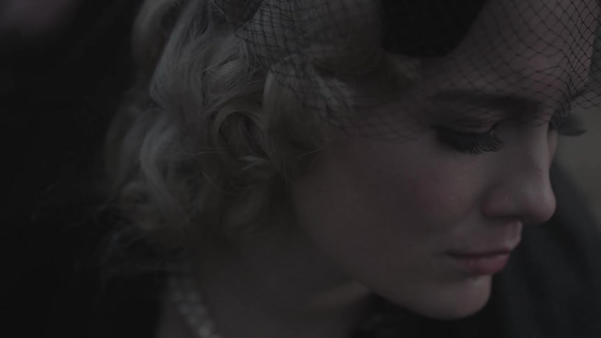 A woman in a black veil looks down