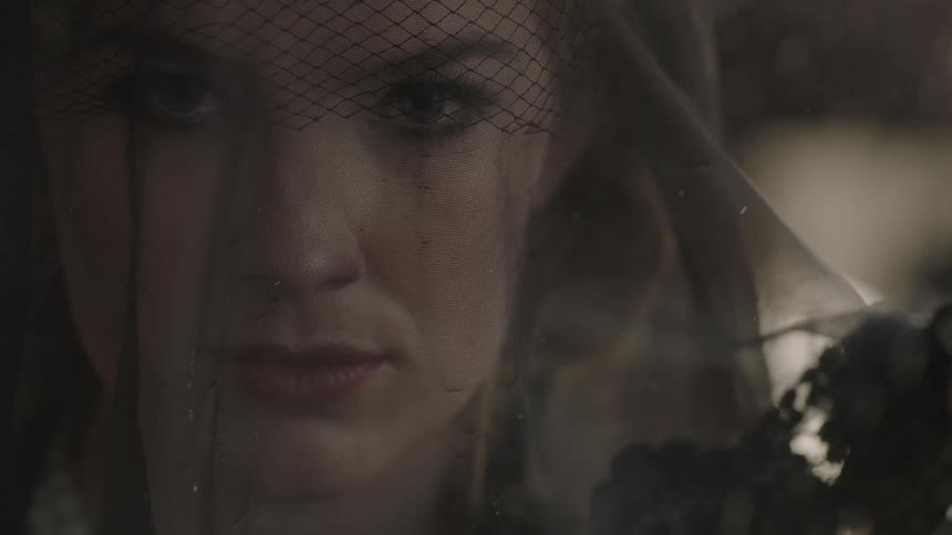 Rain falls on a woman in a veil