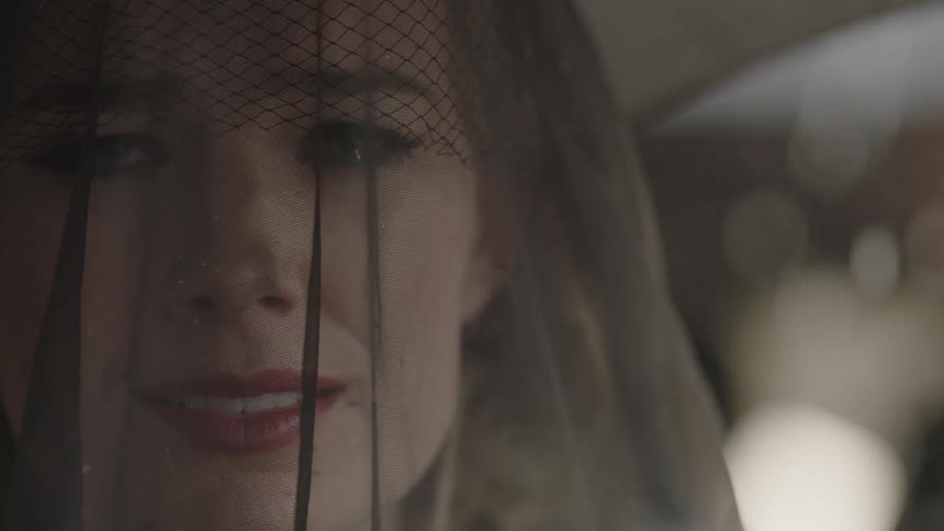 Rain falls around a veiled and mourning woman