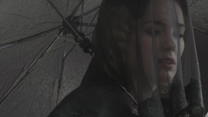 A woman in black holds an umbrella