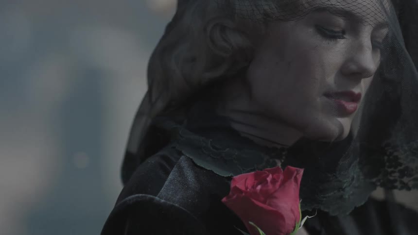 A woman is wearing a veil and holding a rose