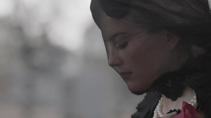 Woman wearing a black veil on a very windy fall day