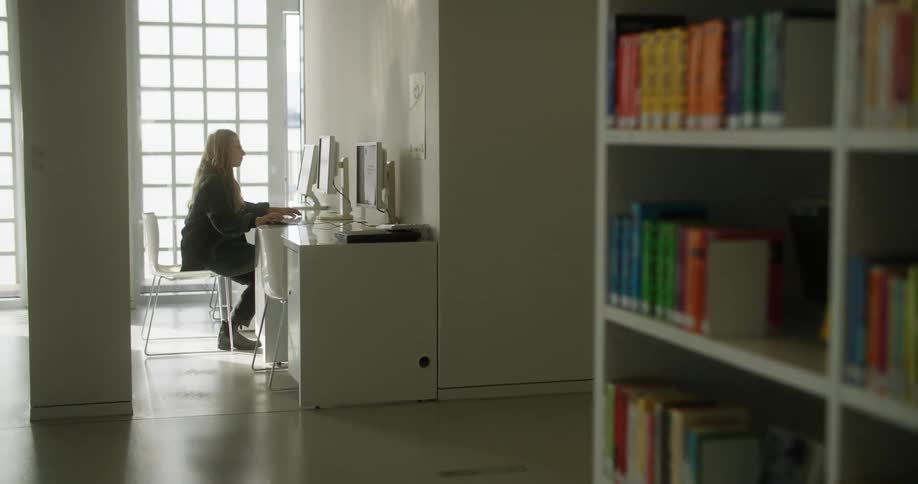 Woman sits in front of computer in library