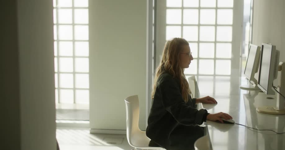 A woman uses a computer along a wall of computers