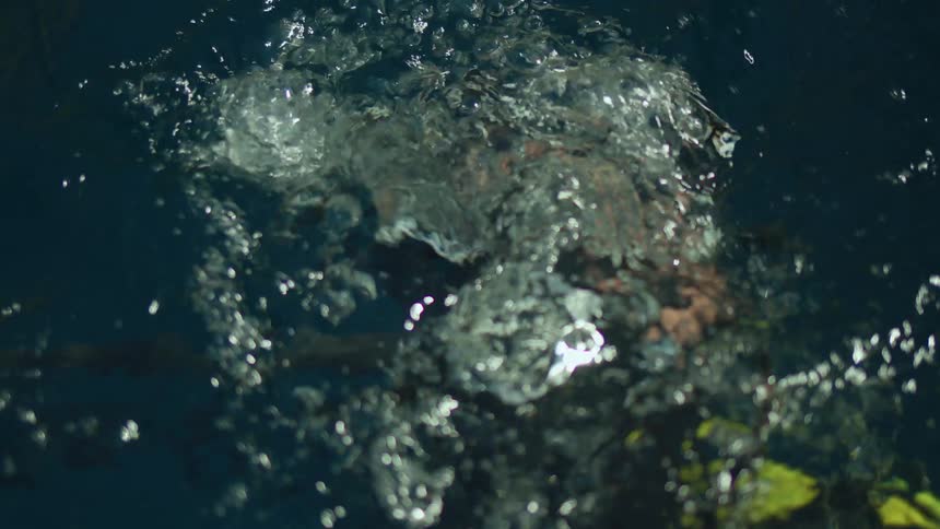 A scuba driver falls backward into the water as he looks up through his goggles