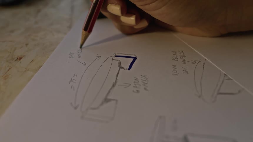 A woman writes notes next to a sketch of furniture