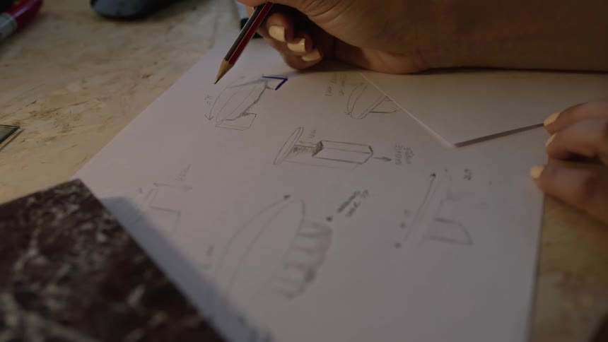 A persons hand using a pencil to sketch on paper