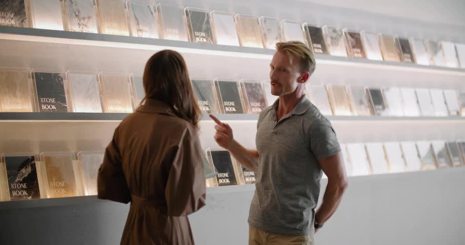 A man and woman talking while looking at books through glass