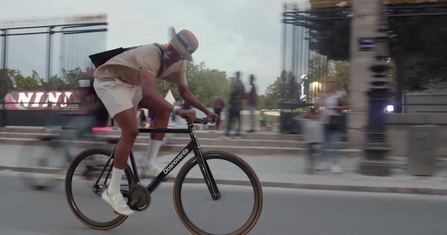 Young happy man drives a bicycle on a street in front of a park in the city
