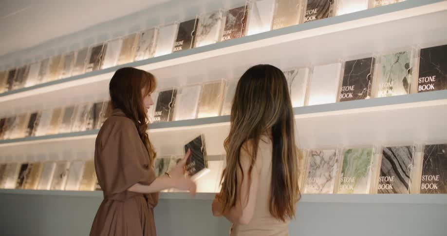 Two women in a retail shopping one is showing the other stone books and explaining them