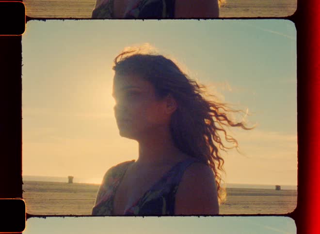 Woman stands on beach on windy day as sun shines down onto her