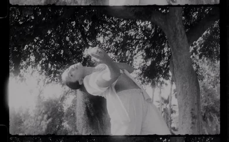 A woman dances hip hop style under a tree