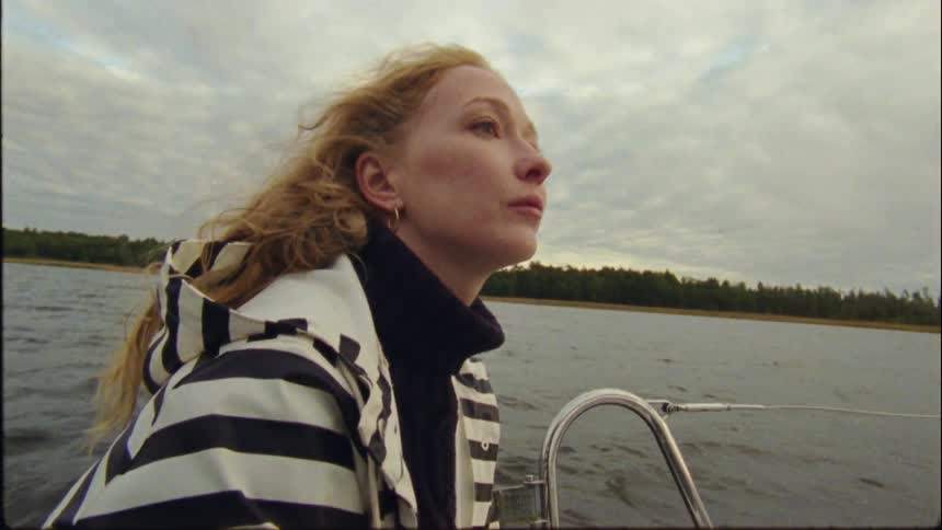 A young woman is on the boat driving on the lake