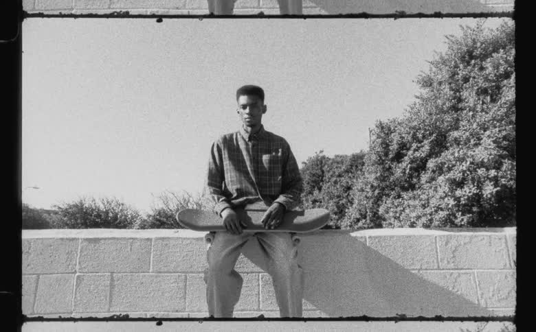 A man sitting on a concrete wall with a skateboard on his lap