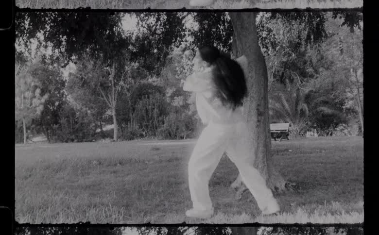 Woman dances in park near tree