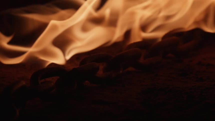 Flames move across the ground and over a chain