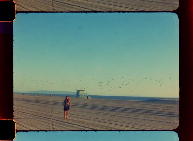 A woman running through the sand as a flock of birds fly behind her