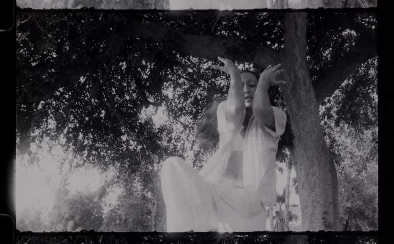 A woman is dancing by a tree