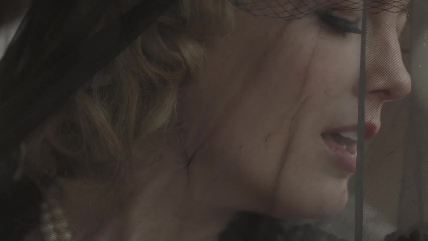 Rain falls around a veiled and mourning woman