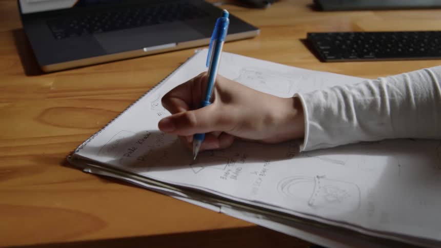 Close up of the hand of a woman writing on a notepad with a pen at the office