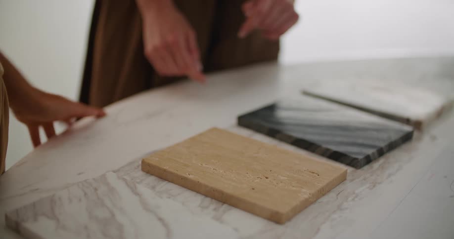 A woman shows another woman some wooden samples with different designs