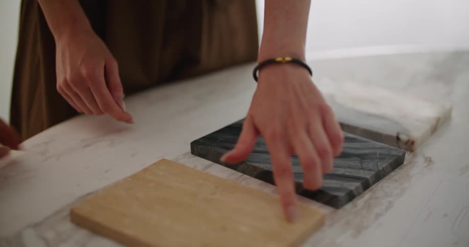 Two women stand in front of a table and look at wooden samples possibly for floors or counters