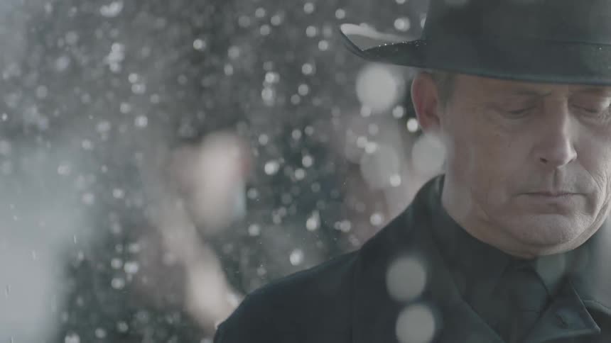 Rain falls on a man in black