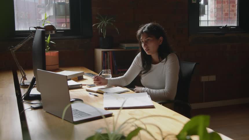 A woman is having a conversation at her computer desk