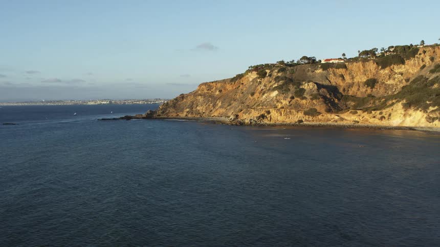 Aerial view of gentle waves washing on a beach next to a cliff at daytime