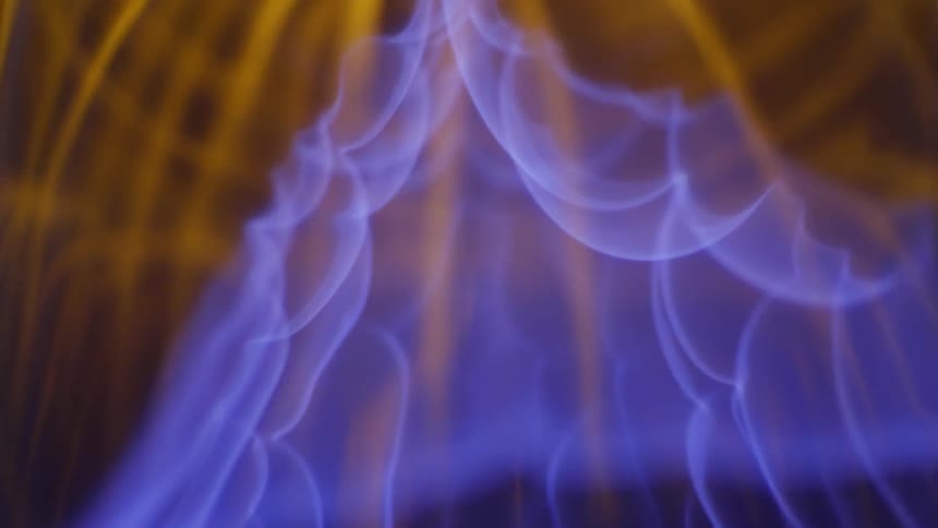 Blue and orange flames ignite in a dark room