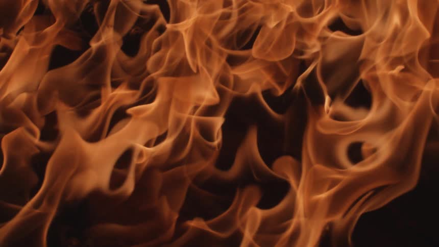 Tall flames move across a dark room