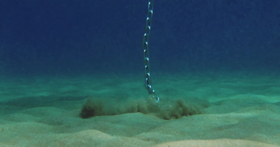 A chain anchor sinks to the bottom of the ocean