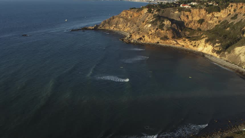 Aerial view of waves gently crashing on a beach in a natural bay
