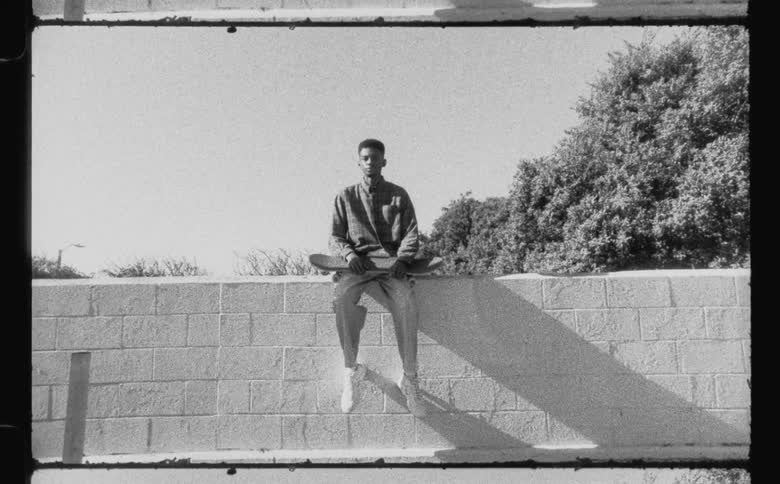 A male is sitting on a ledge and holding a skateboard