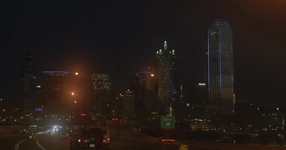 Cars are driving on a highway through a downtown city