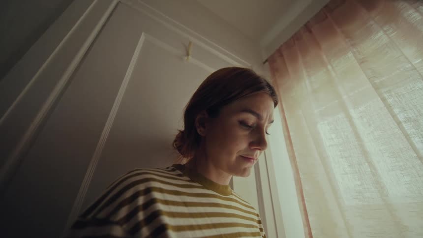 A woman staring down at something and smiling camera pans to reveal a phone